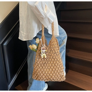 Close-up of handmade woven tote bag with hollow diamond mesh pattern and floral charm