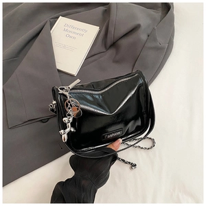 Detail of black patent leather crossbody bag with silver chain and balloon dog charm