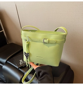 Detail of pistachio green lychee pattern bucket bag with VYGONGZHU logo and silver heart pendant