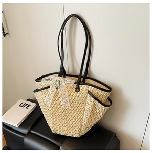 Détail du sac en paille avec nœud en dentelle blanche et bandoulières en similicuir noir