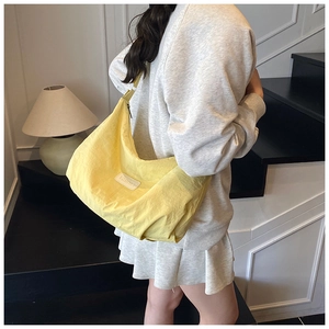 Detail of a bright yellow nylon crescent shoulder bag with a natural wrinkled texture