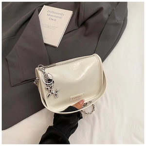 Close-up of white patent leather shoulder bag with a silver balloon dog charm and chain strap