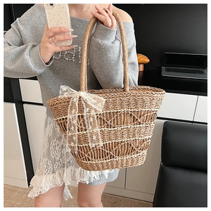 Detail view of woven straw tote bag featuring delicate white lace bow and large capacity