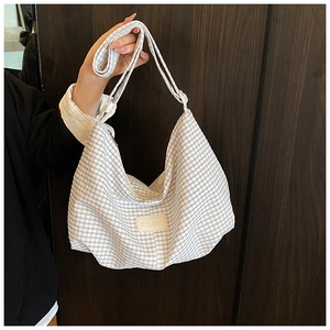 Detail of grey checkered hobo bag featuring logo patch and spacious shoulder strap