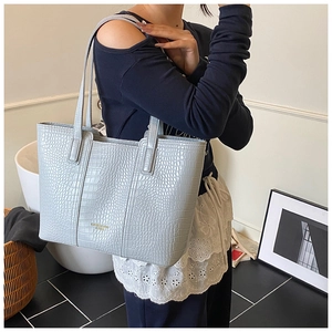 Detail of light blue faux crocodile leather tote bag with elegant gold foil lettering