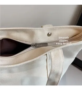 Macro shot of smooth silver metal zipper and snap button on off-white canvas tote bag