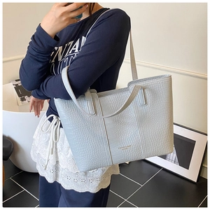 Macro detail of light blue crocodile embossed leather tote bag with gold logo text