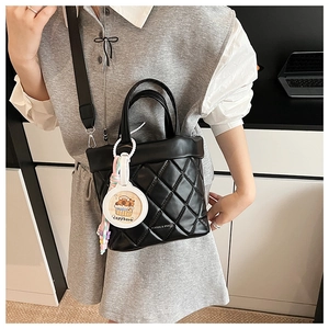 Detail of black quilted leather bucket bag with wide strap and capybara charm