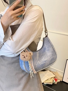 Blue denim hobo shoulder bag with silver metallic trim and brown plush bear charm