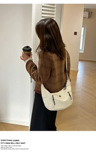Détail d'un sac demi-lune blanc cassé en similicuir texturé avec poches zippées