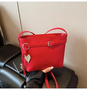 Detail of red lychee textured leather bucket bag with silver heart charm and buckle