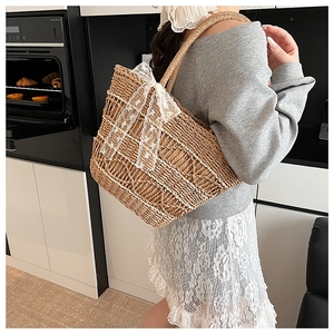 Detail of woven straw tote bag featuring white lace bow and large shoulder strap