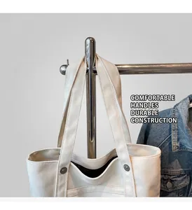 Detail of off-white canvas tote bag with reinforced handles and durable metal rivets