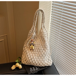 Close-up of cream woven tote bag with intricate hollow mesh and cute doll charm