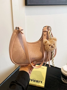 Chic pink half-moon hobo bag with a cute bear charm and stylish ribbon accessory