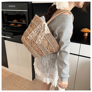Detail of woven straw tote bag with white lace trim and bow in a home setting