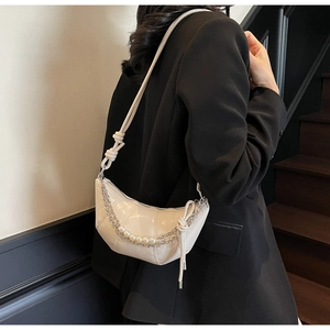 Detail of white glossy croissant bag with pearl chain accessory on black blazer