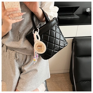 Detail of black quilted crossbody bag with stylish Capybara pendant and logo print