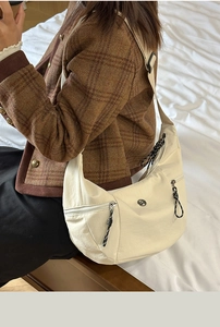 Détail du sac croissant en nylon beige avec bandoulière réglable et logo circulaire
