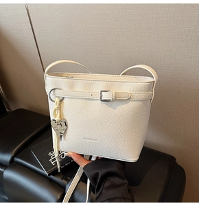 Detail of white lychee pattern bucket bag with leather belt buckle and silver heart pendant