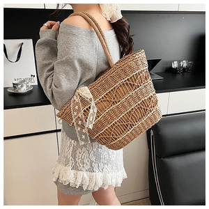 Detailed view of the woven straw tote bag with elegant white lace ribbon decoration