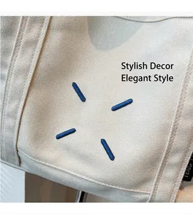 Detail of beige canvas tote bag featuring blue radial stitching and woven brand tag
