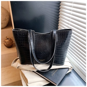 Close-up of black crocodile pattern tote bag with gold lettering in a lifestyle setting