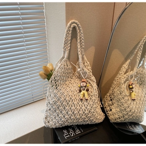 Detailed texture of white handwoven mesh tote bag with a cute cartoon doll pendant