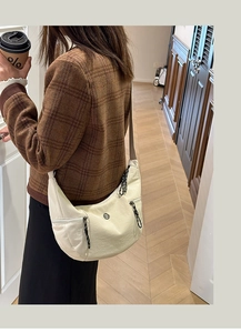 Détail du sac à bandoulière en nylon crème avec sangle réglable et logo argenté