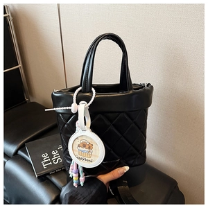 Detail of black quilted PU leather bucket bag with a cute Capybara charm accessory