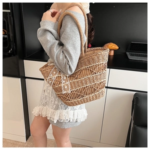 Detail view of woven straw tote bag featuring delicate white lace bow and natural texture