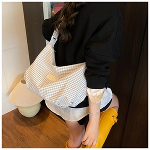 Detail shot of black and white checkered crossbody bag with IZIMIT brand label and wide strap
