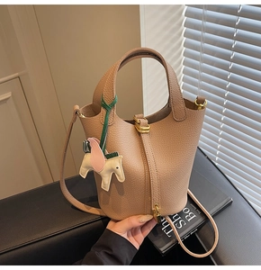 Close-up of litchi pattern leather bucket bag with gold lock and pegasus charm