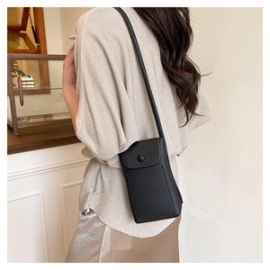 Close-up of black litchi texture leather mini crossbody bag with round snap button