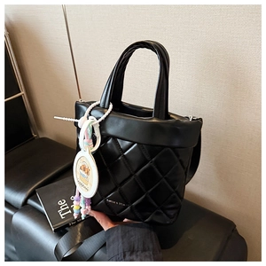 Detail of black quilted leather handbag with capybara charm and beaded accessory decoration