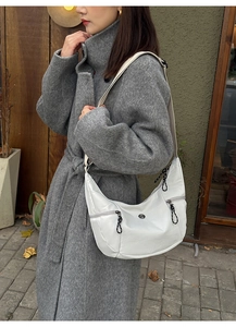 Détail du sac hobo blanc montrant les poches zippées et les tirettes tressées