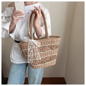 Detail of woven straw tote bag with delicate white lace ribbons for a summer look