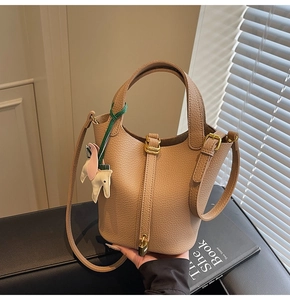 Close-up of beige leather bucket bag with horse charm and golden padlock detail