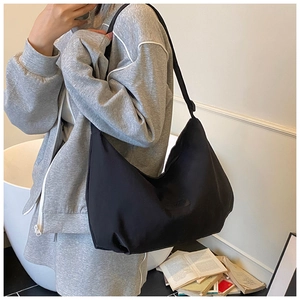 Side view of black crescent shoulder bag in high-density nylon on person with books