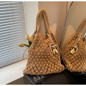 Close-up of beige woven tote bag featuring hollow mesh design and cute girl charm detail