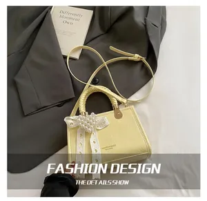 Close-up of a yellow PU handbag featuring braided handles, lace bows and pearl details