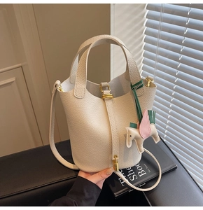 Detail of cream leather bucket bag with metal lock and horse charm decoration