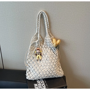 Detail of white macrame tote bag with woven handles and cute yellow tulip charm