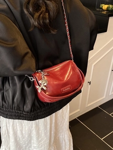 Red glossy leather crossbody bag with metal chain strap and silver balloon dog charm