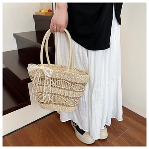 Detail of hand-woven straw tote bag with lace bow decoration and hollow pattern