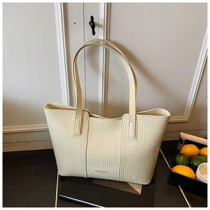 Detail view of cream crocodile pattern tote bag with embossed fashion text and long handles