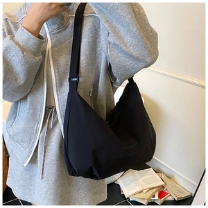 Close-up of black canvas hobo bag with adjustable strap and minimalist brand label