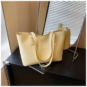Macro view of pale yellow faux leather tote bag showing detailed crocodile embossing texture