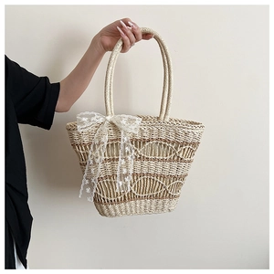 Close-up of hand-woven straw tote bag with lace bow and hollow wave texture details