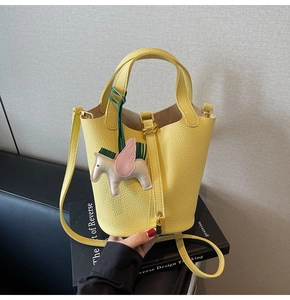 Close-up of yellow bucket bag with lychee grain leather and colorful horse charm